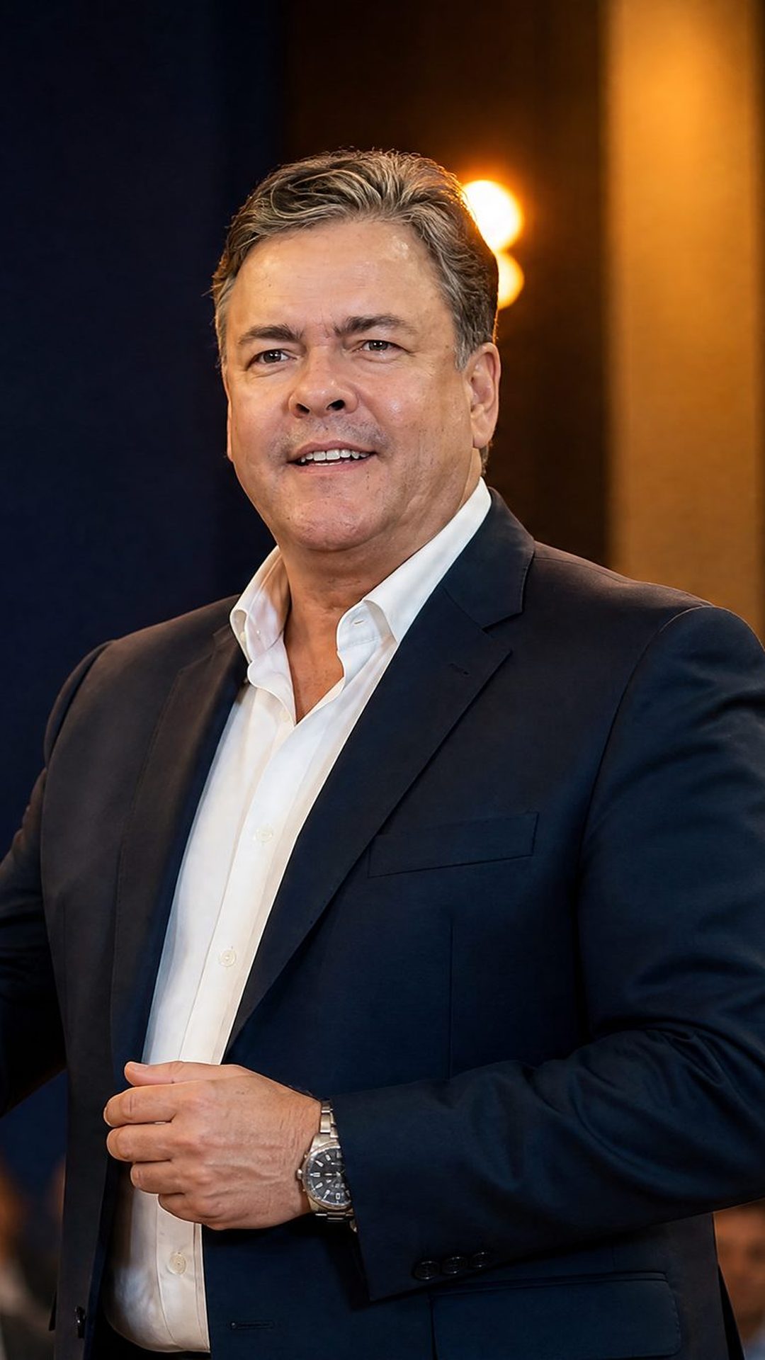 Marco Amaral em palestra, de terno, diante de uma plateia
